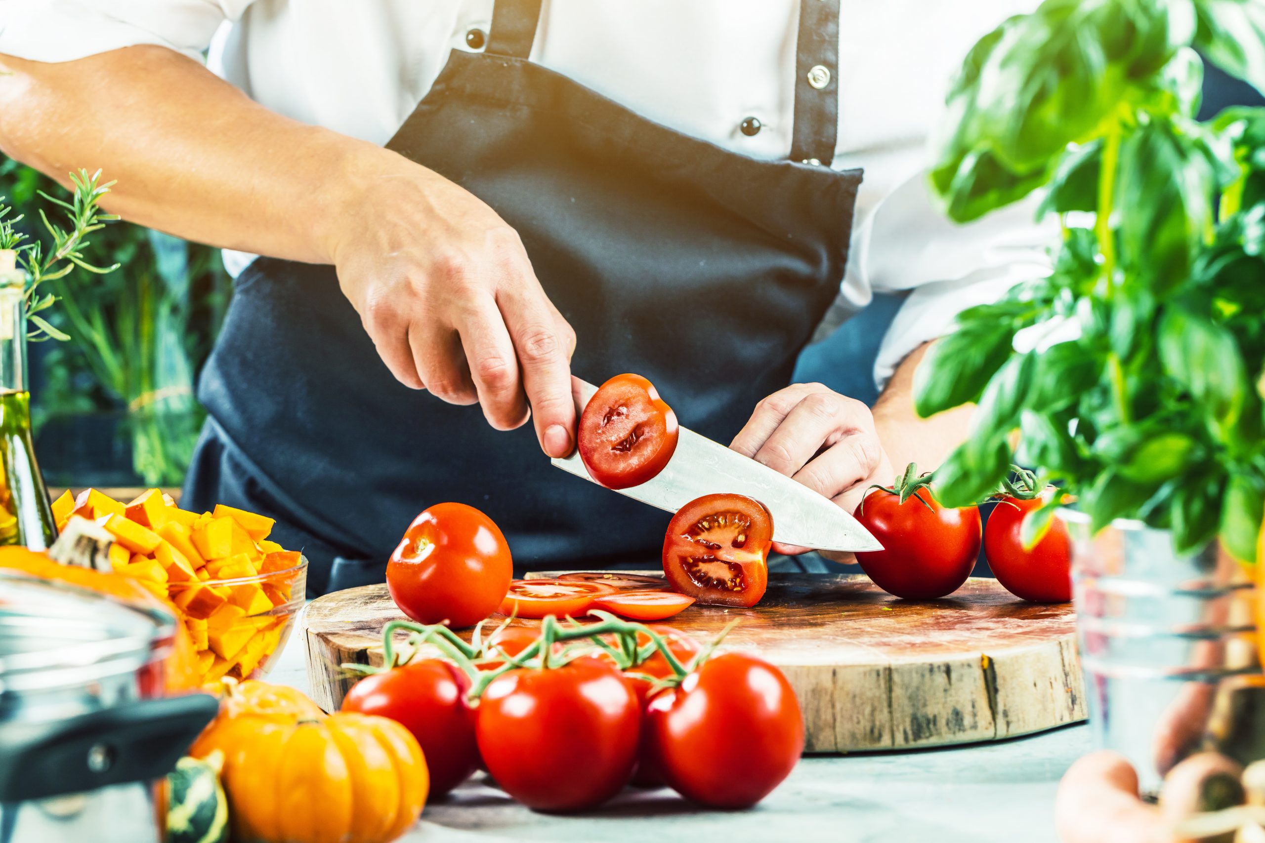 Koch schneidet frische rote Tomaten in Restaurant küche